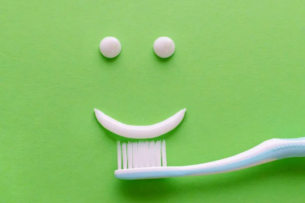 Лицо с улыбкой от белой зубной пасты, концепция ухода за зубами, зубная щетка на зеленом фоне — стоковое фото