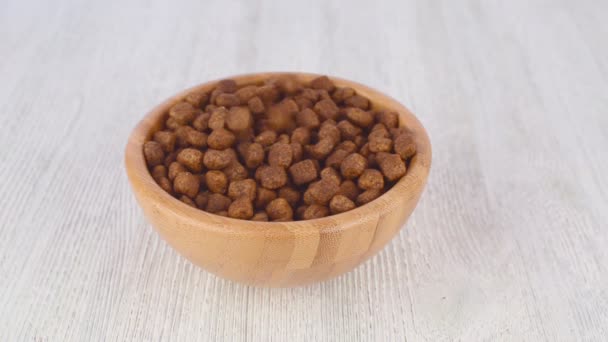 A wooden bowl on the table and falling dog food — Stock Video