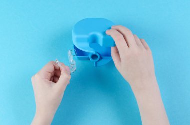 mavi arka plan üzerinde kutu ile ortodontik cihaz ile çocuk el