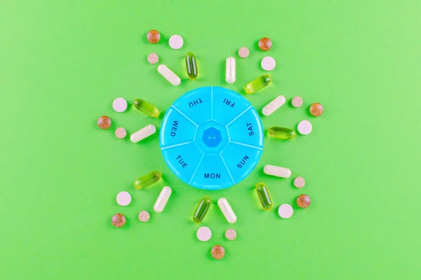 different nutritional supplements for one week and a pills box on green background