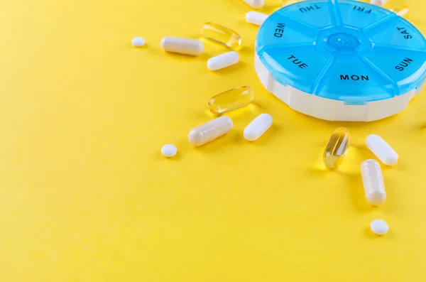 Farmaci diversi per una settimana e una scatola di pillole su sfondo giallo con spazio di copia — Foto Stock