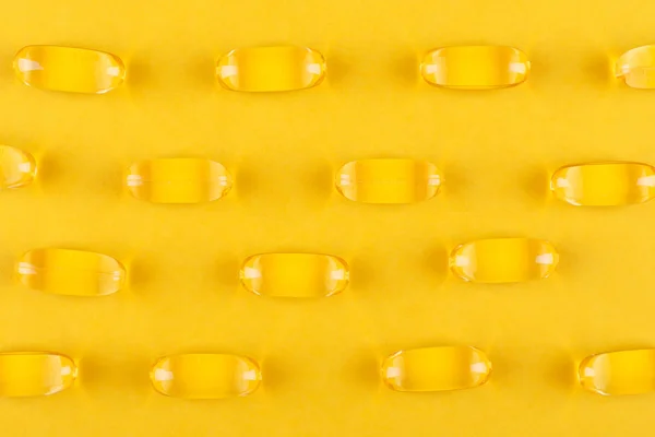 Yellow capsules on yellow background, abstract pattern — Stock Photo, Image