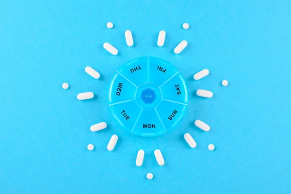 Lek na tydzień z pudełko pigułki na niebieskim tle — Zdjęcie stockowe