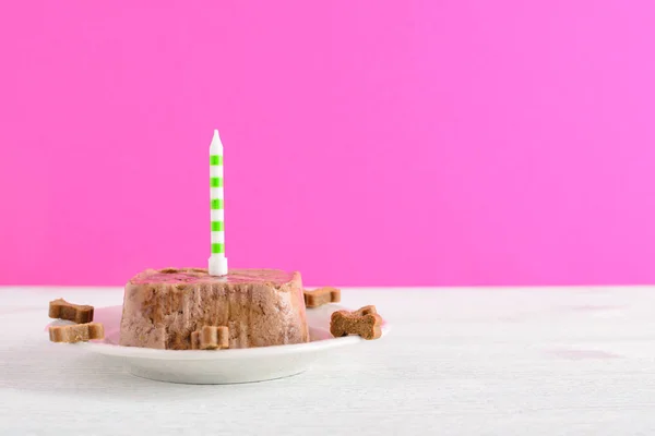 Happy birthday cake for dog from wet food and treats with candle on pink background — Stock Photo, Image