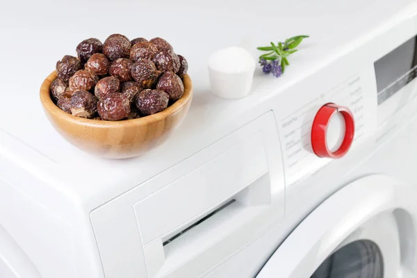 Soap nuts in a bowl on the washing machine and lavender, detergent powder, selective focus — Stock Photo, Image