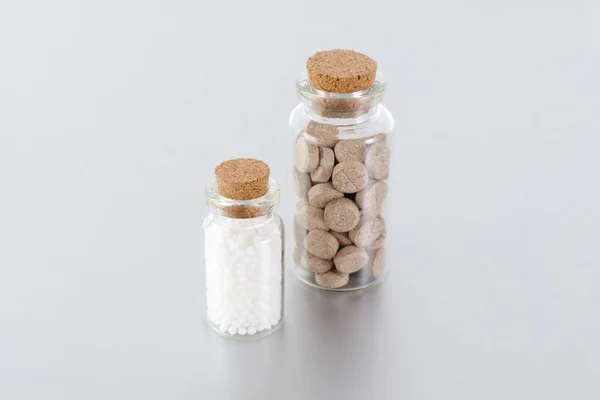 Пляшки натуральної медицини з трав'яними таблетками та кульками на сірому фоні — стокове фото
