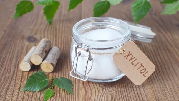 Sugar substitute xylitol, a glass jar with birch sugar on wooden background — Stock Video