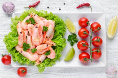 ahşap masada limon ile domates, biber ve sarımsak ile lezzetli pişmiş karides