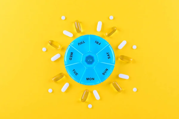 Verschiedene Nahrungsergänzungsmittel für eine Woche und eine Tablettenbox auf gelbem Hintergrund — Stockfoto