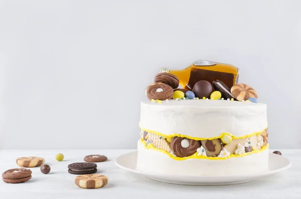Rolig tårta med en flaska alkohol, godis och kakor på grå bakgrund — Stockfoto