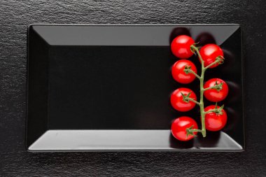 Tabakta taze domates ve siyah arka plan.