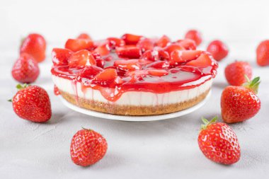 Çilekli cheesecake ve gri masada taze böğürtlen, beyaz arka plan, seçici odak