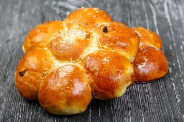 Gri ahşap zemin üzerine serpiştirilmiş kuru üzümlü 7 çiçek şeklinde çörekler.