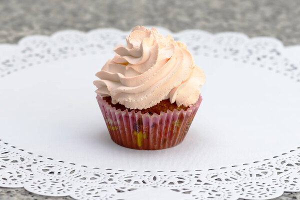 Кекс с клубничным джемом и взбитыми сливками на белой салфетке
