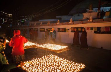 Yaşlı kadın - Avrupa'dan turist nasıl kadınlar göz kulak olun ritüel tereyağı yağ lambaları bir stupa Boudnath, Katmandu, Nepal 4 Şubat 2017 tarih önünde kare fotoğraf arşivi.