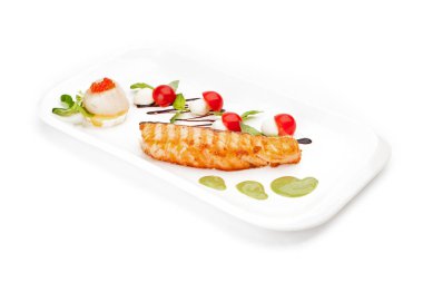 Adet balık filetosu, kızarmış ve beyaz bir tabak üzerinde kiraz domates ile yeşil yaprakları tarafından sunulan hizmet.