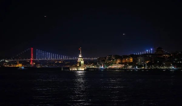 View of an Istanbul, Bridge from Europe to Asia and Maiden tower, on night fires and reflexes on water.