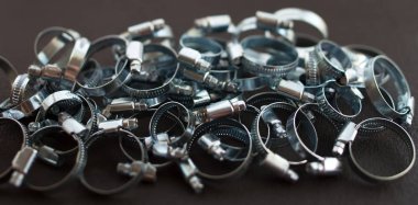 Karanlık yüzeyde çok sayıda metal boru kelepçesi