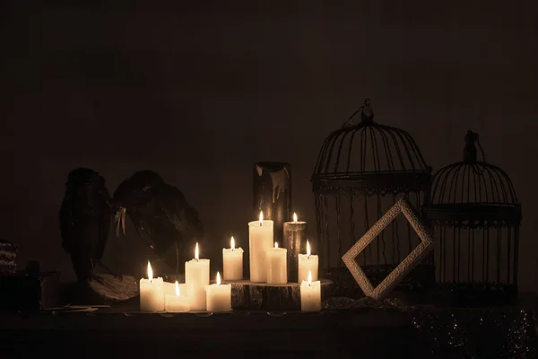 Efigies de dos cuervos, velas y jaulas en el cuarto oscuro . — Foto de Stock