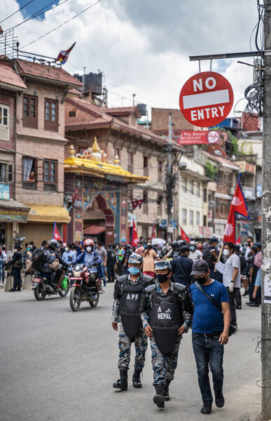 June 14, 2020, Kathmandu, Nepal. AFP Special Forces police are walking under road sign "No entry", along a street full of demonstrators with Nepalese flags and posters protesting corruption and the ineffective fight against coronavirus in Nepal.