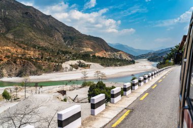 Yolun kenarındaki otobüs penceresinden bir dağ nehri ve dağlar arasında bir vadi çitle bak..