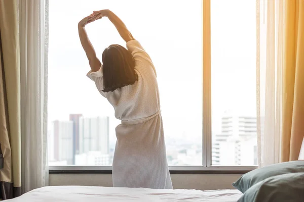 Easy lifestyle Asian woman waking up in weekend morning taking some rest relaxing in comfort city hotel room enjoying world lazy day, having happy life quality balance concept