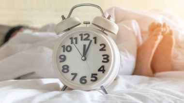 Uyku saati öğlen çalar saat ile ya da gece yarısı yatak odasında tembel bir gün ve sağlıklı bir yaşam dengesi konsepti için uyku zamanı.