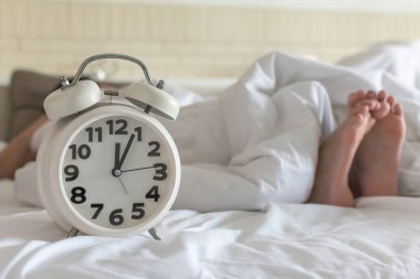 Uyku saati öğlen çalar saat ile ya da gece yarısı yatak odasında tembel bir gün ve sağlıklı bir yaşam dengesi konsepti için uyku zamanı.