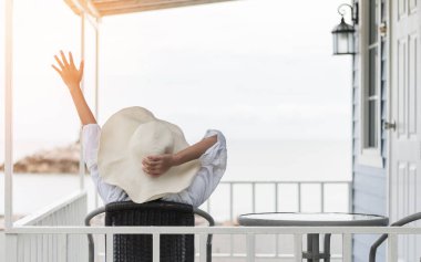 Yaz tatili yaşam tarzı, güneşli bir günde güneş kremi takan genç bir kız, dinleniyor. Kumsaldaki sahil evinin verandasında oturup sağlıklı yaşam kalitesini kutluyor.