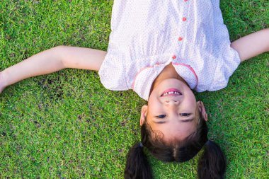 Çevre dostu, mutlu, Asyalı bir çocuğun doğal yeşil çimlerde rahatlayıp güzel doğada yaşaması. 