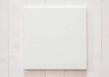 Beyaz boş tuval, beyaz ahşap duvarda resim ve iç dekorasyon için kare boyut.