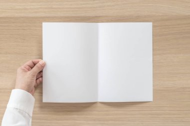 Broşür tasarımı broşür modelini modelle iş adamının elinde A5 boyutlu kağıt şablon çizimi için, ahşap masa üzerinde düz bir şekilde yatıyordu.