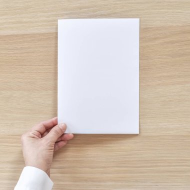 Çift katlı broşür broşür tasarımı A4 boyutunda, yarı katlanmış kağıt yerleşim alanı şablon çizimi için işadamının elinde düzmece, ahşap masadan düz bir görünüm.