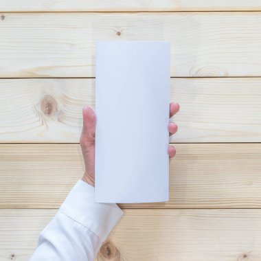 Boş broşür kapak üç katlı el ilanı A4 kağıt şablonu iş adamının elinde ahşap masa üzerinde üst görünüm