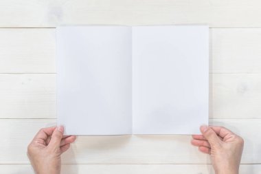 Broşür tasarımı broşür modelini modelle iş adamının elinde A5 boyutlu kağıt şablon çizimi için, ahşap masa üzerinde düz bir şekilde yatıyordu.