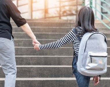 Eğitici okula geri dönmek ya da ilkokul öğrencisinin aile üyelerinin elini tutan sırt çantalarını taşıması ya da okul müdürlüğünden sınıfa giriş binasına kadar yürümesi.