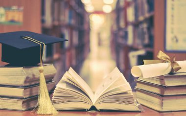 Mezuniyet şapkası, akademik başlık, havan topu ve sınıf veya kütüphane çalışma odasında kitap ve ders kitapları diploması ile eğitim başarısı