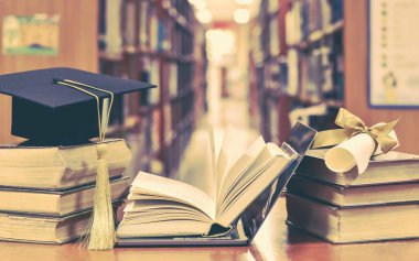 IT bilgisayar dizüstü bilgisayarı, mezuniyet şapkası, akademik şapka, havan topu ve kütüphane çalışma odasında kitap diploması ile E-öğrenim sınıfı ve İnternet eğitim başarısı
