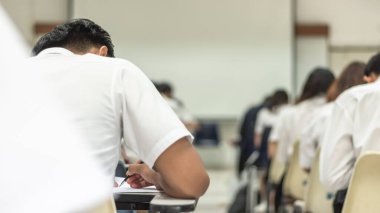 Okul öğrencisi eğitim sınavına giriyor, kabul sınavına giriyor, çok düşünüyor, üniversite sınıfında, eğitim ve dünya okur yazarlık gününde cevap yazıyor.