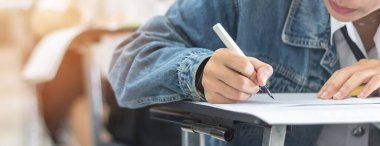 Sınav öğrencisinin eğitim sınavına girmesi, çok düşünmesi, üniversite eğitimi ve dünya okur yazarlık günü konsepti için sınıfta cevap yazması.