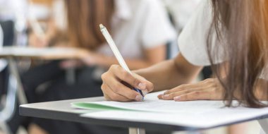 Okul öğrencisi sınava giriyor, çok düşünüyor, eğitim üniversitesine kabul sınavı ve dünya okur yazarlık günü konsepti için sınıfta cevap yazıyor.