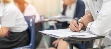 Okul öğrencisi eğitim sınavına giriyor, kabul sınavına giriyor, çok düşünüyor, üniversite sınıfında, eğitim ve dünya okur yazarlık gününde cevap yazıyor.