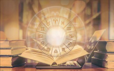 Çevrimiçi burç astrolojisi ve burç çalışmasıyla birlikte burç işareti ve falcılık eğitimi konsepti ile birlikte okul kütüphanesinde eski kitap ve bilgisayar dizüstü bilgisayarının üzerinde burç tekeri var.