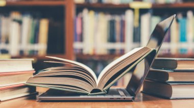 E- öğrenme sınıfı ve eğitim konsepti e-kitap dijital teknolojisi bulanık okul kütüphanesinde bilgisayar defteri açık veya eski kitap yığınları, ders kitabı arşivi koleksiyonu arasında sınıf arkaplanı
