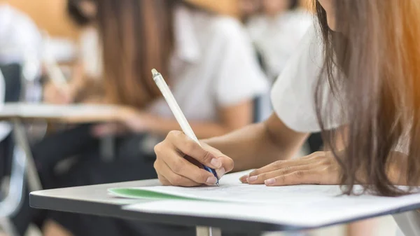 Okul öğrencisi sınava giriyor, çok düşünüyor, eğitim üniversitesine kabul sınavı ve dünya okur yazarlık günü konsepti için sınıfta cevap yazıyor.