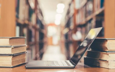 E- öğrenme sınıfı ve eğitim konsepti e-kitap dijital teknolojisi bulanık okul kütüphanesinde bilgisayar defteri açık veya eski kitap yığınları, ders kitabı arşivi koleksiyonu arasında sınıf arkaplanı