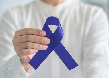 Colectal Colon kanseri erkek sağlığı konsepti için elinde mavi yay renginde kurdele