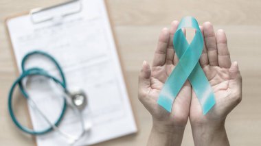 Teal ribbon awareness on woman's hand for Ovarian Cancer, Polycystic Ovary Syndrome (PCOS) disease, Post Traumatic Stress Disorder (PTSD), Tourette's Syndrome, Obsessive Compulsive Disorder (OCD) clipart