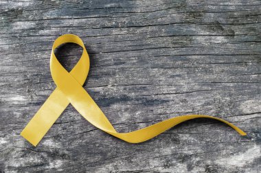 Yellow ribbon symbolic color for Sarcoma Bone cancer awareness and suicide prevention on aged wood (isolated with clipping path) clipart