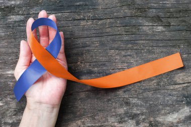 Human rights for family caregivers awareness in orange navy blue fabric ribbon color splashed on human hand old aged background clipart